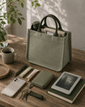 Sage green mini canvas tote with forest green handles holding everyday essentials on a wooden table.