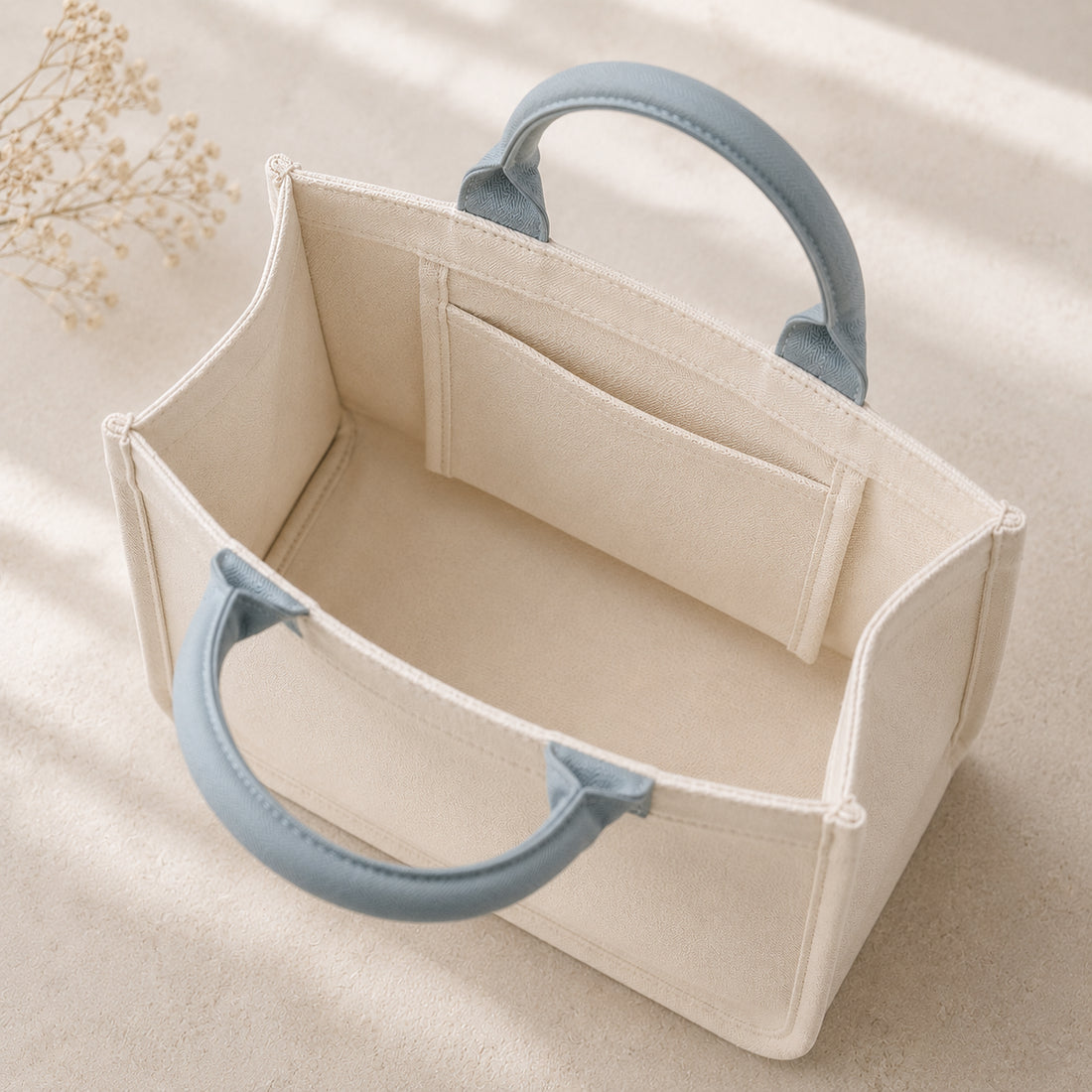 Mini canvas tote in ivory cotton canvas with mist blue handles, soft structured shape and flat bottom.