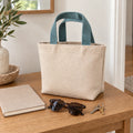Dune Mini Canvas Tote beside a notebook, sunglasses and keys on a warm wooden table.
